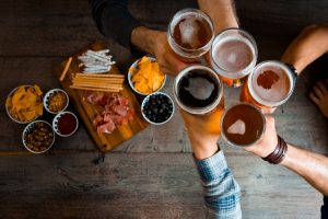 Top view of friends toasting with beer glasses in the pub